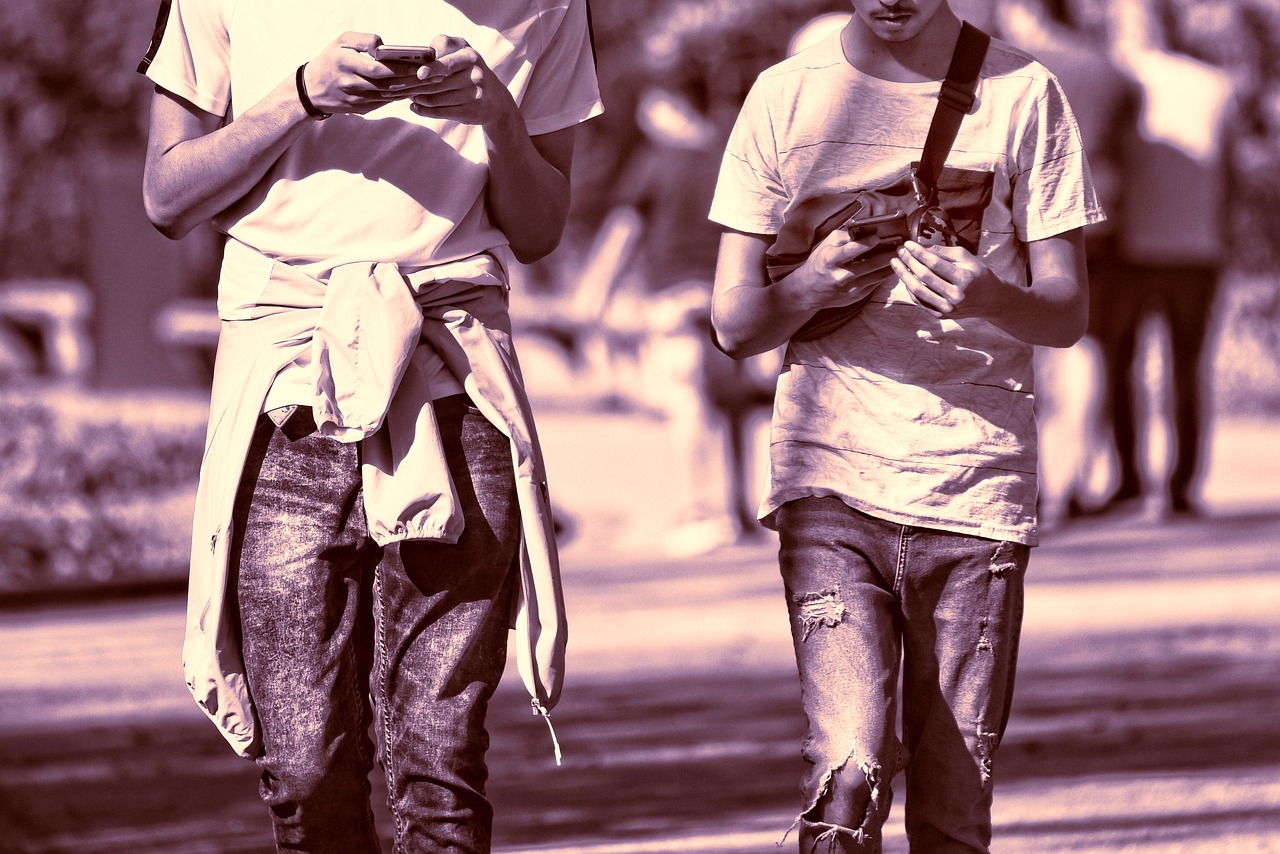 2 jeunes hommes qui marchent avec leur téléphone