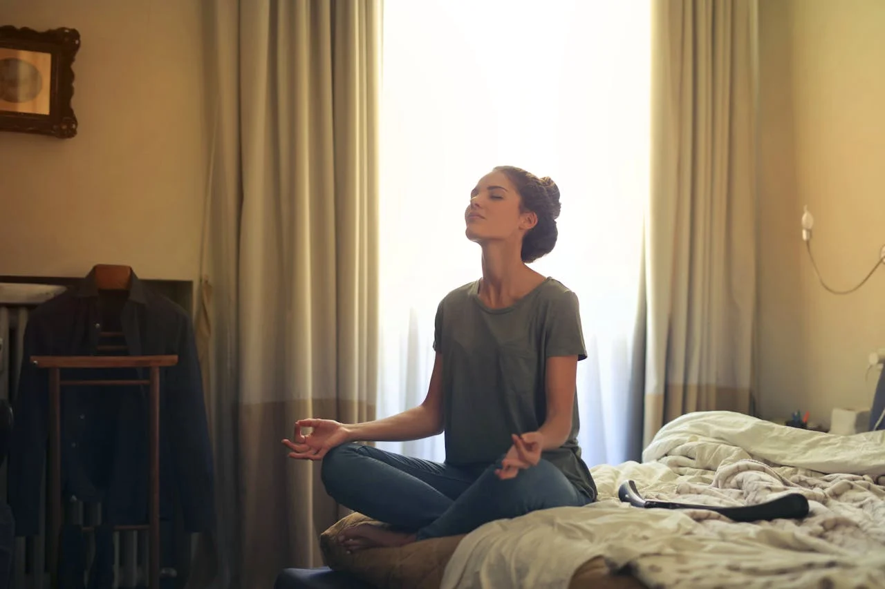 une femme qui pratique la méditation sur sont lit